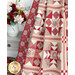 Close up photo of a red and cream patchwork quilt draped over furniture with a small taupe table and bouquet of red and white roses in the background