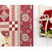 Close up photo of one edge of the patchwork quilt showing border details with a wall sconce filled with red and white flowers in the foreground