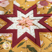 Close up of the center of the folded star design made with white, red, and yellow floral fabrics with a pink center