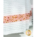 Close up photo of the bottom of a white kitchen towel with floral fabric details