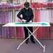 woman using an ironing board as a table to cut fabric in a quilt shop