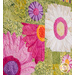 Close up photo of a floral quilt showing applique details of large pink, purple and white daisies with a patchwork green background