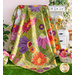 Photo of a colorful floral quilt draped a large white hutch on the grass with baskets of flowers all around