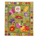 Isolated photo of a large, floral quilt made with green patchwork batiks, and large, colorful applique flowers, on a white background