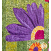 Close up photo of a floral quilt showing applique details of large orange, purple and yellow daisies with a patchwork green background