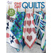 Front of One Day Quilts, showing four finished quilts hanging from a rack