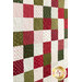 Close up photo of a green, red, and cream Christmas-themed quilt flat against a wall to show quilting stitch pattern