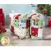 Photo of two mini charm bags on a wooden countertop with decorative zipper pulls and Christmas decor in the background