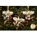 Close up photo of three finished Angel Bell Ornaments hanging on a decorated Christmas tree with lights in the background