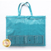 Image of the back of the teal tote, showing one very large vinyl pocket with a creative grids ruler laying over top to show scale.