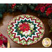 Photo of a Christmas table topper on a wooden table with garland and poinsettias all around