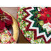 Close up photo of a Christmas table topper and a place setting featuring matching cloth napkins and a red poinsettia