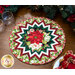 Photo of a Christmas table topper on a wooden table with garland, a place setting, and two glasses.
