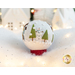 Photo of a wool felt snow globe featuring a small snowman and 2 evergreen trees in a snowy scene, surrounded by white Christmas and winter decor.