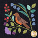 Close up of one quilt block showing a branch growing various flowers with a robin perched at the center
