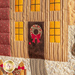 Close up photo of the front door of the applique house in the quilted wall hanging showing wreath detail