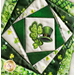 Close up photo of the finished wall hanging featuring offset squares in shades of green with a shamrock and top hat in the center