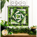 Photo of the finished wall hanging featuring offset squares in shades of green with a shamrock and top hat in the center, on a craft holder in front of a white paneled wall and decorative foliage.