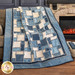 Photo of a cream and blue patchwork rag quilt draped over a couch in front of a fireplace.