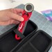 person removing red and black rotary cutter from case