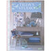 Front cover of the pattern, a desk staged with trinkets in varied grays and blues, featuring some of the projects from the book such as dolls, quilts, & pillows!
