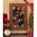 Photo of a winter themed panel quilt featuring a panel with red cardinals and poinsettias on a black background with a rustic textured border, hanging on a tan paneled wall with a chair with a red blanket and winter decor on one side, and a decorated Christmas tree and wrapped present on the other.