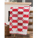 A red and white quilt, draped over a chair