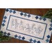 A full view of the completed table runner in wintry whites and blues, staged with pine branches.