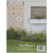 Back of pattern book showing a quilt staged on the side of a house, beside a window and above a garden