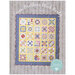 Front of pattern book showing an album quilt in yellow with blue borders, staged on white rustic wood paneling