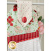 Close up photo of a hanging kitchen towel made with red, white and aqua fabrics in the foreground of a shelf with a bouquet of flowers.