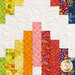 A close up on the quilt, showing fabric and stitching details for the green, yellow, pink, red, purple, and blue fabrics.