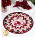 Photo of a floral table topper on a white table with red roses and white plates with red cloth napkins and a houseplant in the background