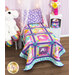 The completed Unicorn Love quilt, staged on a child's bed beside unicorn stuffies and color coordinated furniture.