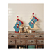 The two completed stockings staged above a rustic wood desk, surrounded by winter themed trinkets.