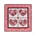 photo of a pink, red, and white wall hanging featuring four red hearts in quadrants, isolated on a white background