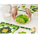Someone placing a plate of shamrock cookies onto the table, the placemats visible in the foreground and behind the model.