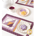 A wide shot of the table, showing the two completed May placemats facing each other. A plate of cookies that match the mats sits between them with a teapot and cup of tea.