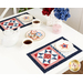 A white table set with patriotic decor and the two completed July placemats, holding white plates with beautifully iced star shaped cookies. 