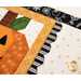 A super close up on the smiling jack-o-lantern and the laser cut scallop border, demonstrating fabric and topstitching detail.