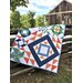 Image of another sample quilt, in white, navy, orange, and green.