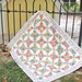 Cover photo for the pattern, showing the completed quilt, staged in a yard with a black fence and a yellow shed in the background.
