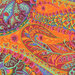 Close up of Fabric featuring multicolor modern paisley designs on a tangerine orange background.