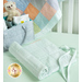 The completed Changing Pad, halfway rolled up and staged in a crib with mint green sheets, rolled up and neatly tied.