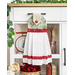 The completed hanging towel in blue, red, and cream, staged on a kitchen cart with cooking utensils, a scale, flowers, and books.