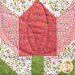 Close up of a pieced fabric block featuring pink and green fabrics making a rose