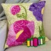 One of the featured projects, a floral design on a pillow. Spools of coordinated thread sit in a row in front of the project.