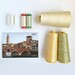 The contents of the fifth box, 6 spools of thread and a postcard, spread out and isolated on a white background.