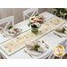 The completed Flower Girl Table Runner staged atop a white table, set with coordinating plates, napkins, and a green pot of matching flowers. 