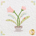 Close up on a block featuring applique details on two pink tulips in a little teacup planter.